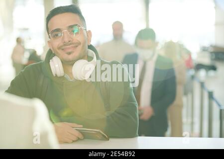 Ein junger Mann lächelt dem Flughafenarbeiter zu, während er an der Rezeption steht Schalter am Flughafen Stockfoto