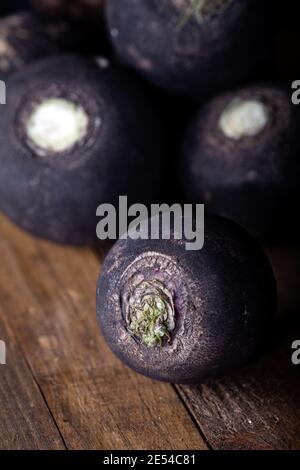 Frische rohe schwarze Radieschen auf Holzhintergrund. Stockfoto