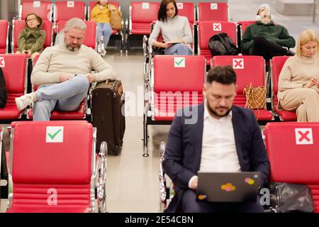 Personen, die in Stühlen im Wartezimmer des Flughafens sitzen Und warten auf ihre Abreise Stockfoto