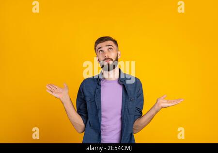 Wer weiß. Verwirrt kaukasischen Kerl zuckende Schultern auf orangen Studio Hintergrund, Panorama Stockfoto