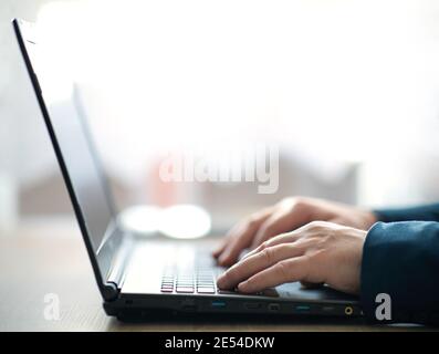 Man's Hände tippen auf einem Laptop-Tastatur. Ein Mann in einer Büroarbeit schreibt auf einem Laptop. Selektiver Fokus Stockfoto