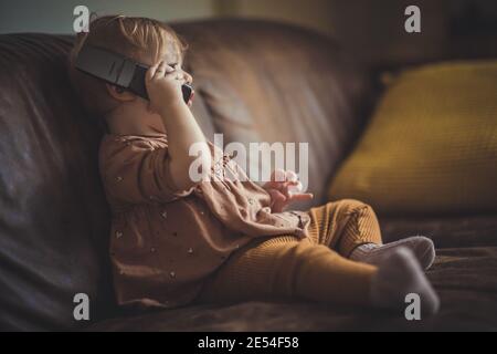 ZWOLLE, NIEDERLANDE - 13. Feb 2020: Kleines Mädchen sitzt auf dem Sofa und spricht am Telefon Stockfoto