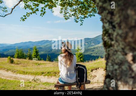 Ausflug in die Karpaten. Frau Tourist Wandern und entspannend bewundern Landschaft sitzt unter Baum mit Rucksack. Reisen im Sommer Ukraine Stockfoto