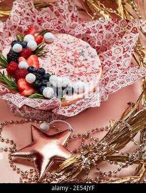 Kuchen mit Schlagsahne, frischen Erdbeeren, Heidelbeeren, Brombeere und Himbeere auf rosa Hintergrund. Bild für ein Menü oder eine Süßwarenkata Stockfoto