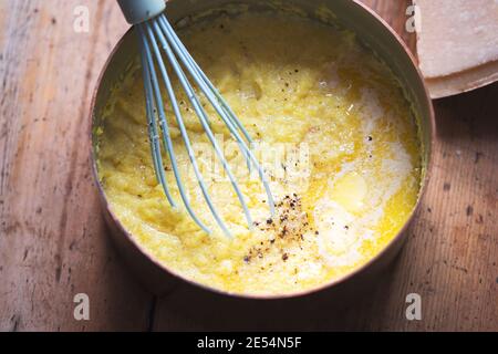 Gekochte Polenta mit Parmesan, Butter, Salz und Pfeffer. Polenta wird hergestellt, wenn Maismehl in Wasser und Hühnerbrühe gekocht wird. Stockfoto