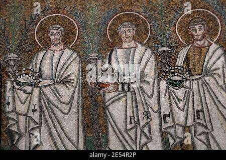 Drei von 26 männlichen christlichen Märtyrern gehen in einer Prozession. Detail aus dem byzantinischen Mosaik in der Basilica di Sant’Apollinare Nuovo in Ravenna, Emilia-Romagna, Italien. Das Mosaik entstand in den 500er Jahren n. Chr., wenige Jahre nachdem Ravenna von den Ostgoten erobert wurde. Stockfoto