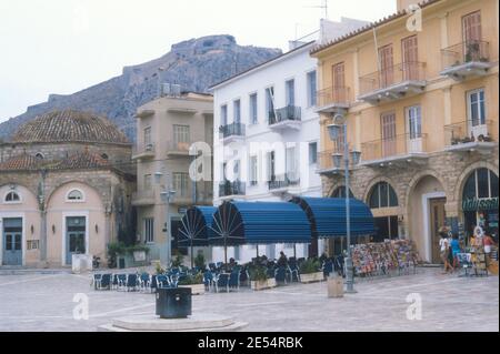 1986 Griechenland - Palamidi ist eine Festung östlich der Akronauplia in der Stadt Nafplio in der Region Peloponnes im Süden Griechenlands. Eingebettet auf dem Kamm eines 216 Meter hohen Hügels, wurde die Festung von den Venezianern während ihrer zweiten Besetzung des Gebiets (1686–1715) gebaut. Die zerstörte Festung kann vom Syntagma Platz, Plateia Syntagmatos, Konstitutionsplatz in Nafplion mit dem Trianon - die alte Moschee und Cafés, Nafplion, Peloponnes, Griechenland, EU, Europa gesehen werden Stockfoto