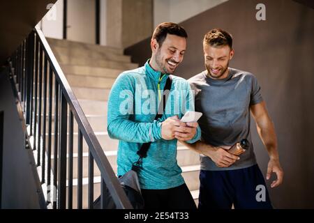 Gutaussehende Fit Männer Freunde sprechen, lächeln nach dem Training im Fitnessstudio Stockfoto