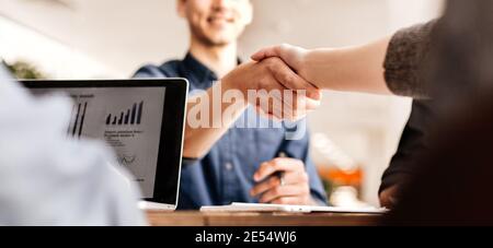 Nahaufnahme. Lächelnder junger Mann, der mit seinem Geschäftspartner die Hände schüttelt. Stockfoto