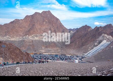 Touristen auf dem Parkplatz des Hatta Wasserdamms genießen die felsigen Berge und die malerische Natur während der Pandemie Zeit. Stockfoto