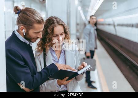Lächelndes junges Paar, das auf der U-Bahn-Plattform steht. Stockfoto