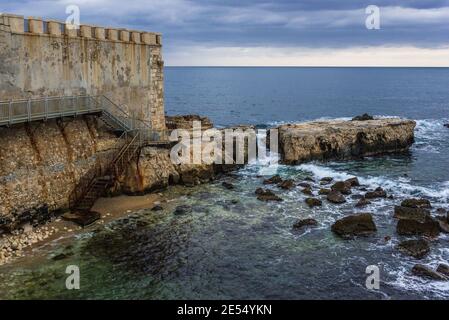 Sehen Sie sich auf die charakteristischen Felsen und Mauern der Insel Ortygia, historischen Teil der Stadt Syrakus, südöstlichen Ecke der Insel Sizilien, Italien Stockfoto