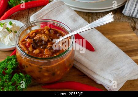 Frisch gekochte Bohnensuppe mit Hühnerfleisch serviert Glasschale auf Holztisch Stockfoto