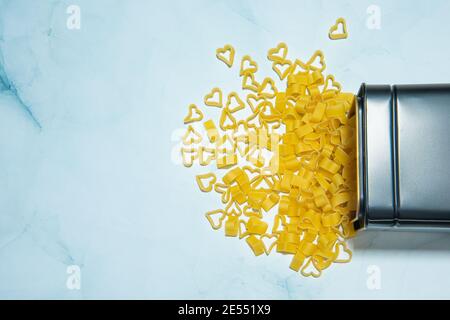 Essen Hintergrund und valentine-Konzept. Pasta in Herzform auf blauem Marmorboden. Konzept der Pasta-Liebhaber. Pasta verschüttet aus der Box. Hochwertige Fotos Stockfoto