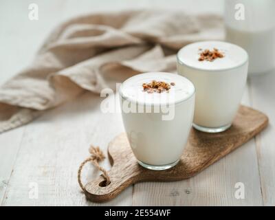 Kefir, Buttermilch oder Joghurt mit Müsli. Joghurt im Glas auf weißem Holzhintergrund. Probiotische kalt fermentierte Milchgetränk. Darmgesundheit, fermentierte Produkte, gesundes Darmflora-Konzept. Kopierbereich Stockfoto