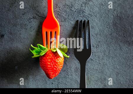 Minimalistisch elegant, schwarze Gabel und eine Erdbeere auf schwarzem Hintergrund Stockfoto