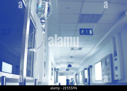 Intravenöses System im Krankenhausflur mit verschwommener Person in der Ferne. Stockfoto