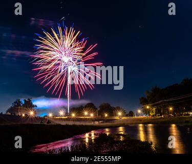 Prattville, Alabama, USA - 4. Juli 2017: Feuerwerk am 4. Juli mit Silhouette eines Paares am Ufer des Baches. Stockfoto