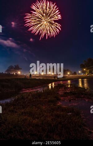 Prattville, Alabama, USA - 4. Juli 2017: Feuerwerk am 4. Juli mit Silhouette eines Mannes mit einer Taschenlampe stehend. Stockfoto