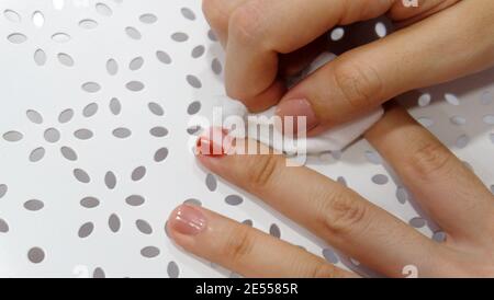Hand abreiben roten Nagellack von Fingernägeln mit weißer Baumwolle. Stockfoto