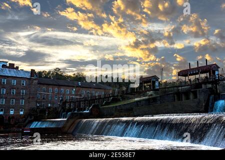 Prattville, Alabama, USA - 20. Dezember 2016: Wasserfall am alten Mühlenteich mit der Continental Gin Company im Hintergrund mit einem dramatischen Sonnenuntergang Stockfoto