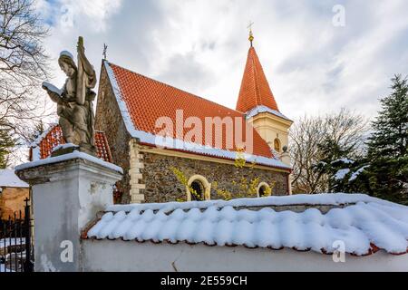 Prag, Tschechische Republik - Januar 13 2021: Blick auf die gotische Steinkirche von Jakob dem Großen mit Tor und heiligen Statuen in Petrovice. Wintertag. Stockfoto