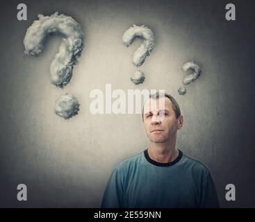 Skeptischer Mann mittleren Alters, der zur Kamera schaut. Mann mittleren Alters mit einem nachdenklichen skeptischen Look trägt lässiges T-Shirt auf weißem Hintergrund. Stockfoto