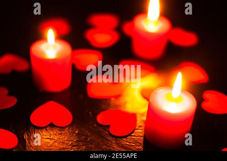 Schwarzer Hintergrund mit Kerzen und Herzen am Valentinstag Stockfoto