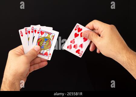 Männliche Hände halten Kombination von Royal Flush Poker-Karten auf dunklem Hintergrund. Casino, Glück und Glück Konzept Stockfoto