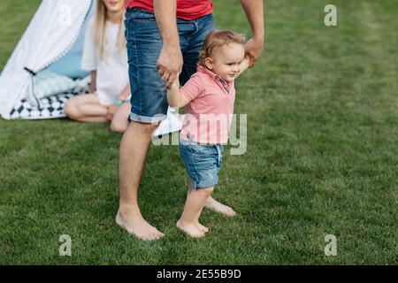 Glückliche Familie verbringen Zeit zusammen draußen im Garten. Kind Spaß mit seinen Eltern spielen auf dem Rasen. Stockfoto