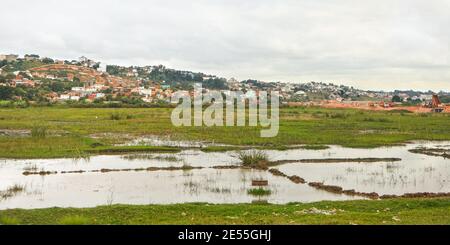 Antananarivo, Madagaskar - 24. April 2019: Typische Landschaft während des bewölkten Tages in der Nähe von Madagaskar Hauptstadt, Häuser auf kleinen Hügeln Hintergrund, Bau Stockfoto