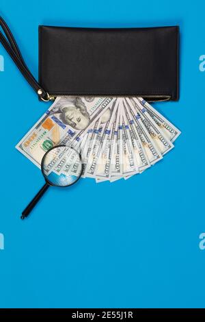 Schwarze Brieftasche mit hundert Dollar Scheinen auf einem blauen Hintergrund Stockfoto