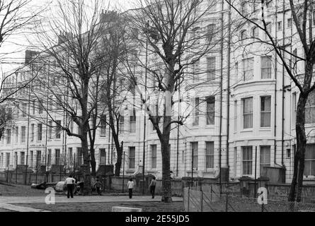 Großbritannien, West London, Notting Hill, 1973. Heruntergekommene und heruntergekommene, große, vierstöckige Häuser werden langsam restauriert und neu dekoriert. *Diese Beschriftung muss auf Fakten überprüft werden. Powis Square Erholungsgebiet. Die Rückseite der Häuser, die auf den Platz zurück liegen, scheint abgerissen worden zu sein und ein modernes terrassenförmiges Gebäude wurde errichtet. (Diese Beschriftung muss überprüft werden)*. Stockfoto