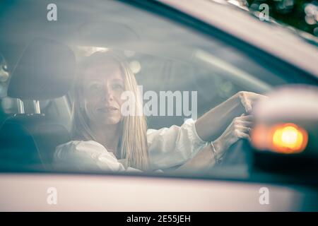 Hübsche Frau im mittleren Alter am Steuer von ihr Auto pendeln zur Arbeit Stockfoto