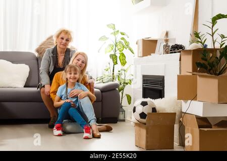 Drei Personen sitzen zusammen auf dem Boden. Sie sind mit Kisten voller Sachen umgeben Stockfoto