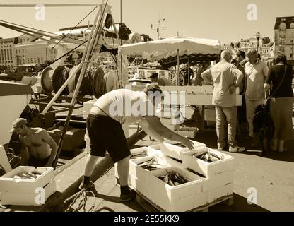 Frischer Fang wird ausgeladen und auf dem nahe gelegenen Street Fish Market am Pier am Hafen verkauft. Trouville-sur-Mer, Frankreich. Sepia historisches Foto Stockfoto