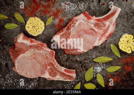 Nahaufnahme der rohen Schweinekotelett Rippe mit Gewürzen auf grauem Hintergrund. Draufsicht. Stockfoto