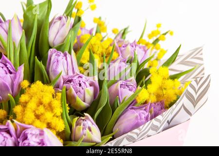 Bouquet von lila Tulpen und gelben Mimosen in rosa Box auf weißem Hintergrund, Nahaufnahme, Seitenansicht. 8. März, 14. Februar, Geburtstag, Valentinstag, Mutter, Stockfoto