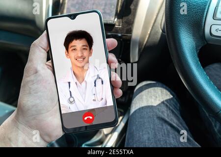 Ein lächelnder Arzt, der mit gekreuzten Armen posiert, trägt ein Stethoskop auf dem Smartphone-Bildschirm. Telemedizin oder telemedizinisches Konzept. Stockfoto