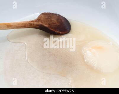 Weißer Schmalz schmelzen in Pfanne mit braunem Holzlöffel Stockfoto