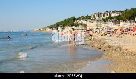 Die Leute entspannen sich am Strand. Trouville-sur-Mer und das nahe gelegene Deauville sind beliebte Sommerresorts in der Normandie. Paar laufen. Stockfoto