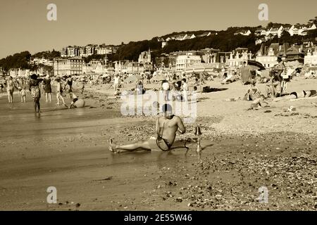 Junger Mann, der am Strand mit Shisha relaxt. Trouville-sur-Mer und das nahe gelegene Deauville sind beliebte Sommerresorts in der Normandie. Sepia historisches Foto Stockfoto