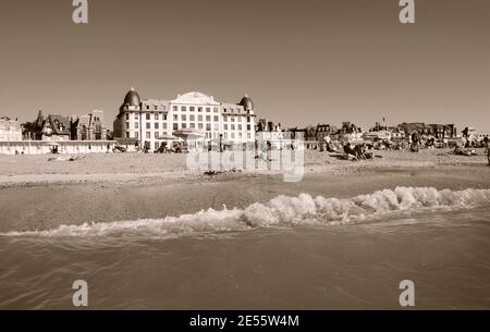 Die Leute entspannen sich am Strand. Trouville-sur-Mer und das nahe gelegene Deauville sind beliebte Sommerresorts in der Normandie. Sepia historisches Foto Stockfoto