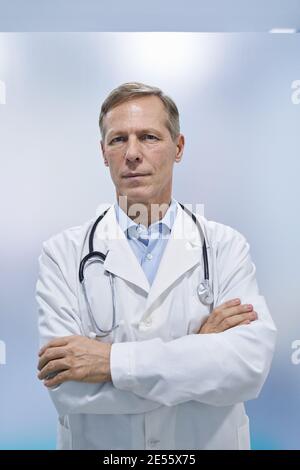 Selbstbewusste ältere professionelle Arzt stehende Arme gekreuzt Blick auf die Kamera. Stockfoto