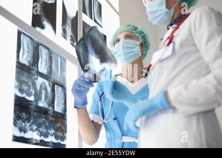 Zwei Ärzte, die medizinische Schutzmasken tragen, untersuchen Röntgenstrahlen Stockfoto