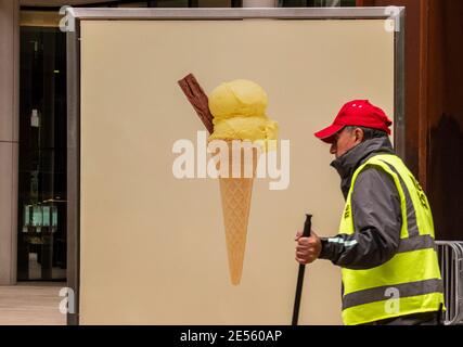 Mann trägt hohe Vis Weste arbeiten von Plakat mit Eis-Kegel in der Nähe Kings Cross. Stockfoto