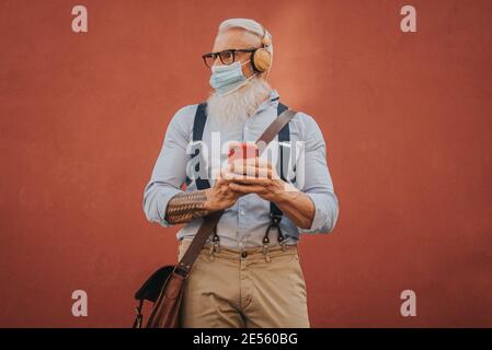 Ein älterer Mann in Hüftklamotten und Brille und lang Weißer Bart hört Musik Fokus auf den Kopf Stockfoto