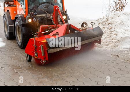 Schneereinigungsprozess in der Winterstadt. Schneeräumschlepper Schneeräumung von der Fahrbahn mit speziellen Rundspinnbürste. Stockfoto