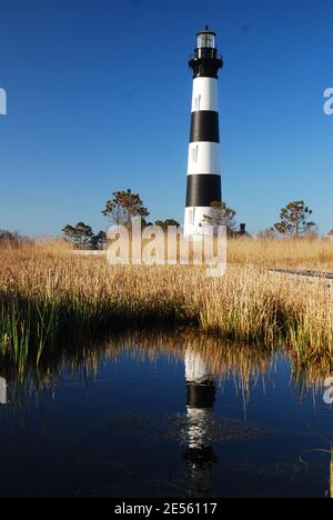 Der hoch aufragende Bodie Island Lighthouse, am Outer Banks von North Carolina, spiegelt sich in der nahe gelegenen Sumpf Stockfoto