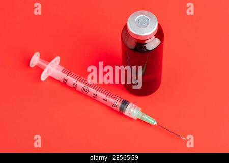 Eine Nahaufnahme einer hygienischen Einweg-Spritze aus Kunststoff mit orangefarbenem Fläschchen auf schwarzem Hintergrund. Stockfoto